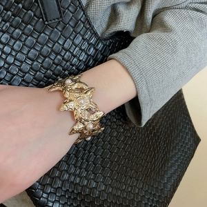 Detail of gold starfish bracelet with pearls featuring a hammered metal texture