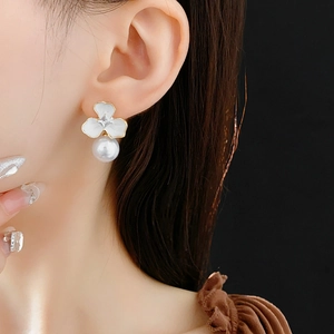 Elegant white floral earrings with pearl drops shown as worn by a model in close-up shot