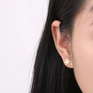 Close-up of elegant golden flower petal stud earrings on female model's ear