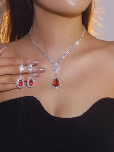 Detailed close-up of a silver bridal jewelry set with sparkling red teardrop pendants