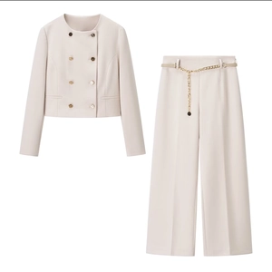 Elegante tailleur beige due pezzi con giacca doppiopetto e pantaloni ampi con cintura a catena