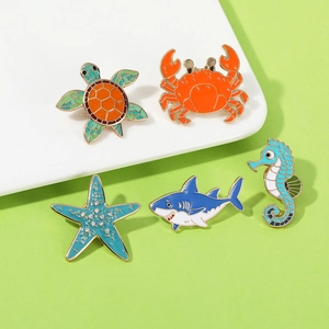 Set of five sea creature enamel pins featuring turtle, crab, starfish, shark and seahorse