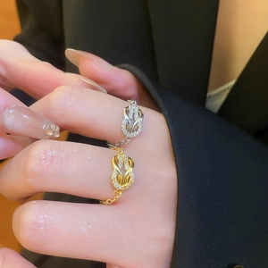 Detail showing gold and silver chain rings with interlocking zircon knot on a finger