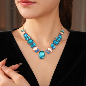 Close-up of luxury gold necklace featuring large blue and iridescent crystal gemstones