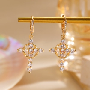 Close-up of golden cross earrings with sparkling cubic zirconia in a refined style