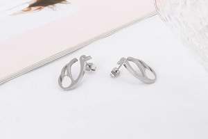 Close-up of elegant silver swan stud earrings with white enamel finish on fabric