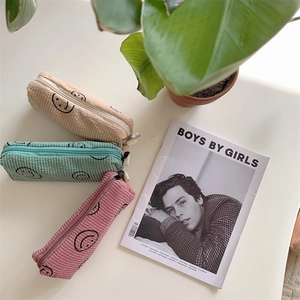 Flat lay of colorful corduroy cosmetic bags with smiley faces and fashion magazine