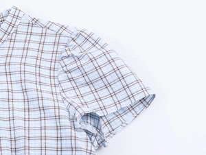 Detail of blue and brown checkered short dress showing fabric texture and sleeve stitching