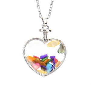 Detailed macro view of heart-shaped glass pendant filled with colorful natural stones