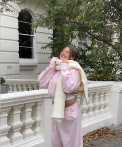 Pink knitted hooded cardigan and pants set paired with a soft beige winter scarf