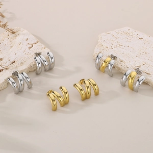 Three-layer C-hoop earrings in gold, silver, and mixed tones on textured stone