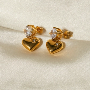 Macro detail of 18k gold plated heart earrings with zircon star engraving on silk