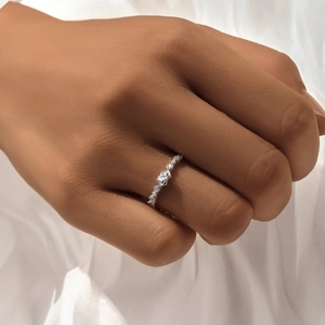 Close-up of S925 silver bow ring featuring small zircons on a white fabric background