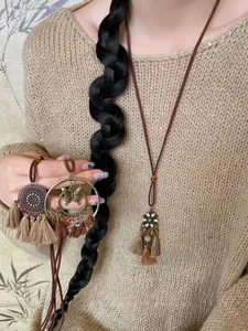 Detail of bohemian layered necklace with vintage bronze discs and silk tassels on a model