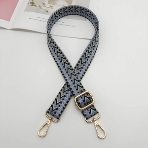 Detail of adjustable geometric woven strap with purple and green patterns and gold hooks