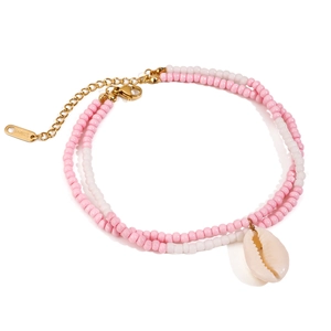 Detail of pink and white beaded anklet with golden shell pendant on white background