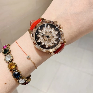 Close-up of a women's red leather watch with a spinning gold diamond snowflake dial