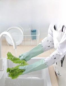 Action shot of waterproof long-sleeved gloves cleaning lettuce in a modern kitchen sink