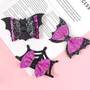 Glittering purple and black Halloween bat wing and spider web bows on white background