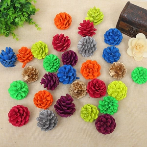 Close-up of assorted colorful painted natural pine cones on beige textured fabric surface