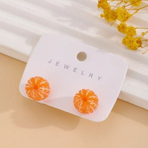 Detailed macro view of orange citrus fruit resin earrings on a white jewelry display card