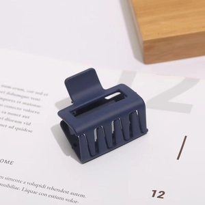 Detail of matte dark blue rectangular hair claw clip with hollow geometric design