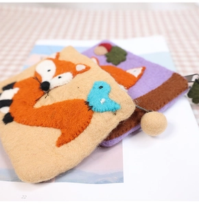 Detailed texture of handmade wool felt fox coin purse with cute pompom and bird charms