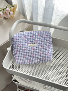 Close-up of quilted cosmetic bag with pink bow patterns and a woven label detail