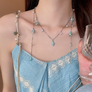 Détail d'un collier argenté multicouche avec étoile de mer bleue, coquillages et perles