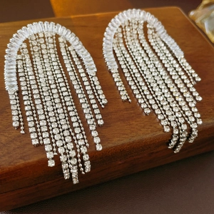 Detail view of silver tassel earrings with sparkling crystals on a wooden background