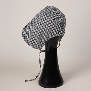 Detail of baby bonnet showing black and white checkered pattern and long cotton straps