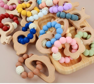 Close-up of beech wood animal teething rings and colorful silicone beads on a tray