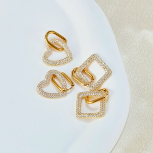 Detail of gold heart and square huggie earrings with sparkling pavé cubic zirconia