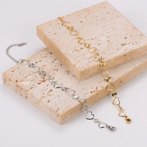 Détail de bracelets en chaîne avec cœurs dorés et argentés sur plaques de pierre et fermoir