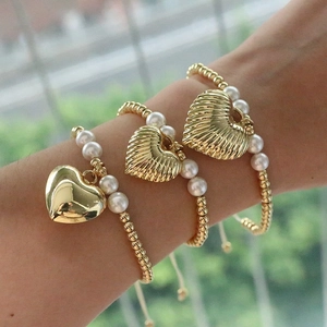 Close-up of a three-piece gold bead and pearl bracelet set with a large heart pendant