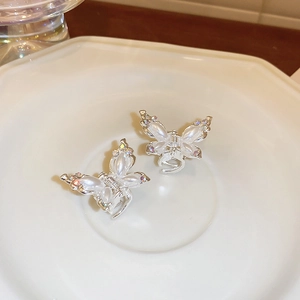 Detailed close-up of two silver butterfly hair claws with pearls and rhinestones on a tray