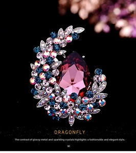 Macro shot of silver crescent brooch with large purple drop crystal and blue rhinestones