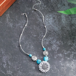 Detail of bohemian silver sunflower pendant with turquoise beads and carved roses