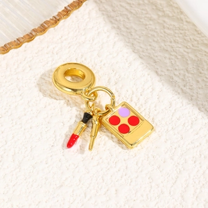 Detail of gold charms featuring lipstick, makeup brush and colorful eyeshadow palette