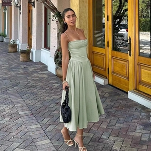 Elegant light green strap dress with A-line silhouette and waist detail in outdoor setting