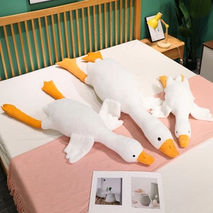Three sizes of soft cartoon white goose plush toys arranged on a cozy bed with warm lighting