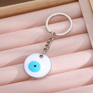 Detail of blue Evil Eye keychain on pink velvet texture with silver metal ring