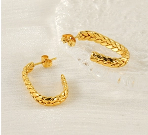 Macro detail of gold-plated twisted rope C-hoop earrings with retro woven texture