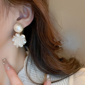 Gros plan d'un mannequin portant des boucles d'oreilles fleurs blanches et perles