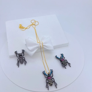 Exquisites Käfer-Schmuckset mit Goldkette und bunten Kristallen auf weißer Box