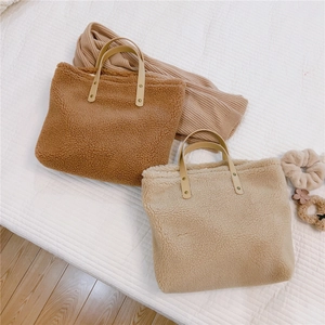 Detail of plush lamb wool tote bags with faux leather handles and metal rivet reinforcement