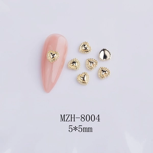 Macro detail of 5x5mm golden hollow heart nail art charms with beaded metal texture