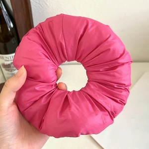 Detail view of a oversized puffy hot pink fabric scrunchie with a soft textured finish