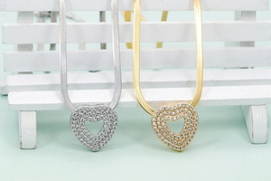 Detail of gold and silver hollow heart necklaces with sparkling cubic zirconia on flat chains