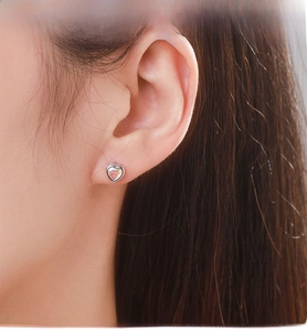 Détail des boucles d'oreilles cœur en argent 925 avec pierres d'opale sur l'oreille